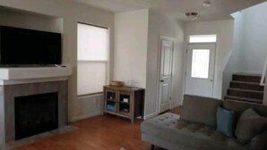 Una sala de estar con chimenea, un sofá y un televisor.