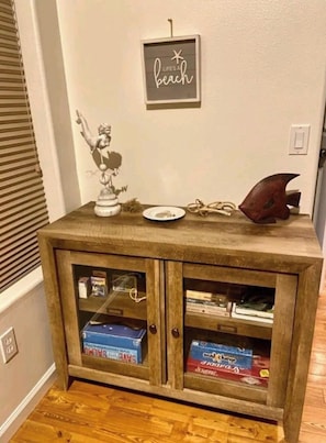 A wooden cabinet with glass doors, a decorative fish, a small statue, and a sign that reads 'LIFE'S A beach'. - Cute Convenient Comfortable House (Coos Bay)