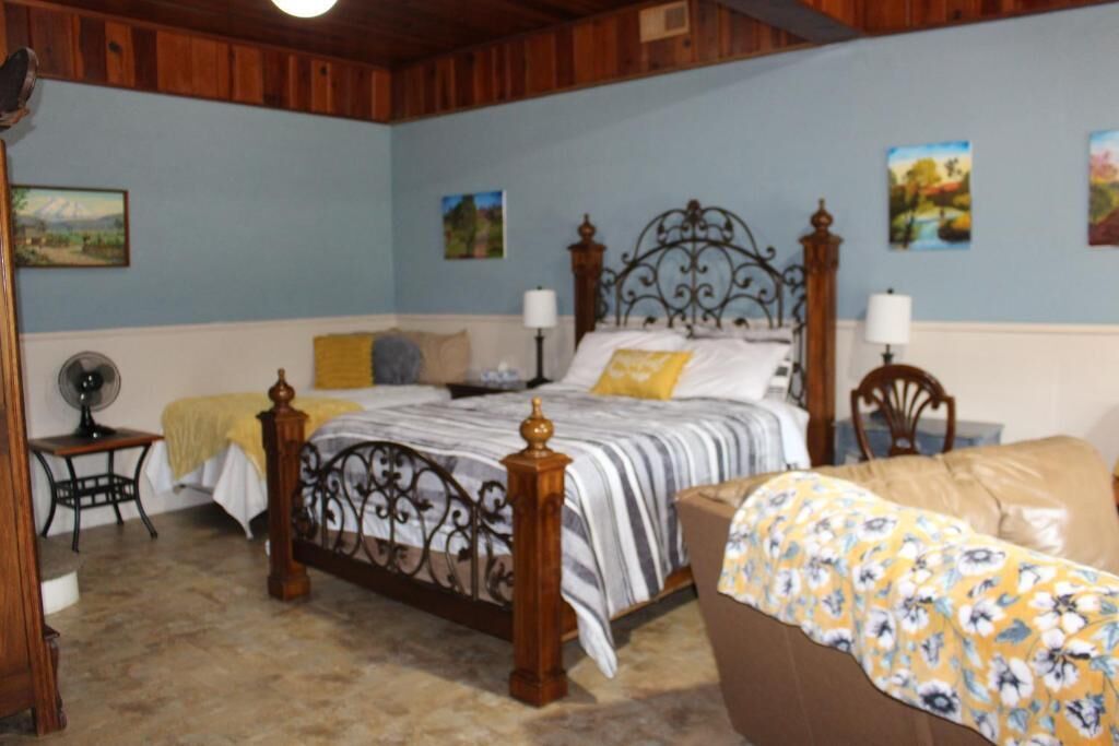 A bedroom with a large bed, a smaller bed, a nightstand, and a chair.
