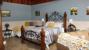 A bedroom with a large bed, a smaller bed, a nightstand, and a chair.