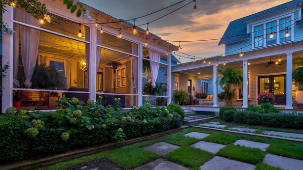 A two-story house with a covered porch, large windows, and a garden with a stone pathway. - Summer Kitchen Cottage/Lake Carolina/Colombia,S.C./Harborside Community (Columbia)