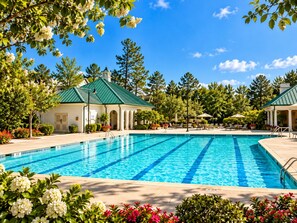 Une piscine à l’eau d’un bleu cristallin, entourée d’une végétation luxuriante et bordée d’un bâtiment doté d’un toit végétalisé.