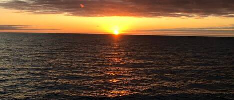 A sunset over a calm sea with clouds in the sky.