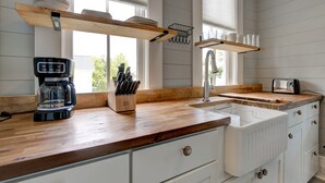 A kitchen with wooden countertops, white cabinets, a coffee maker, and a knife block. - Summer Kitchen Cottage/Lake Carolina/Colombia,S.C./Harborside Community (Columbia)