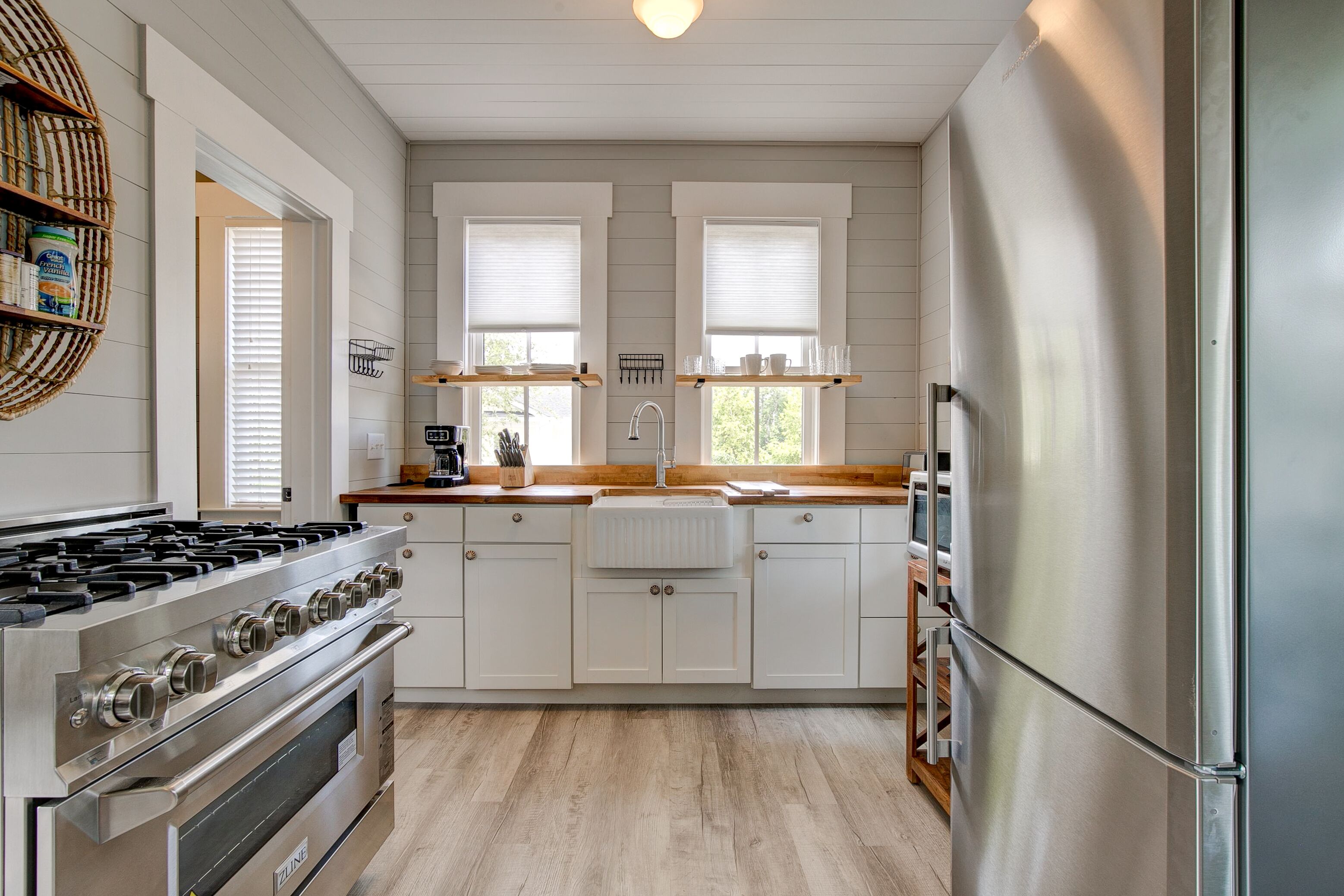 A modern kitchen with white cabinets, stainless steel appliances, and wooden countertops.