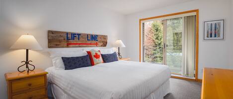 A bedroom with a bed, two bedside tables, a ceiling fan, a window with a view, and a 'Lift Line' sign on the wall.