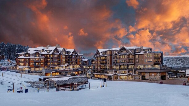 Un grand chalet à plusieurs étages, avec un télésiège visible au premier plan.