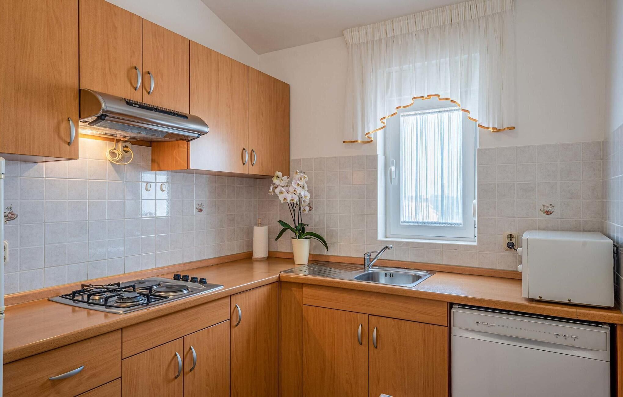 A compact kitchen with wooden cabinets, a gas stove, a sink, and a dishwasher.