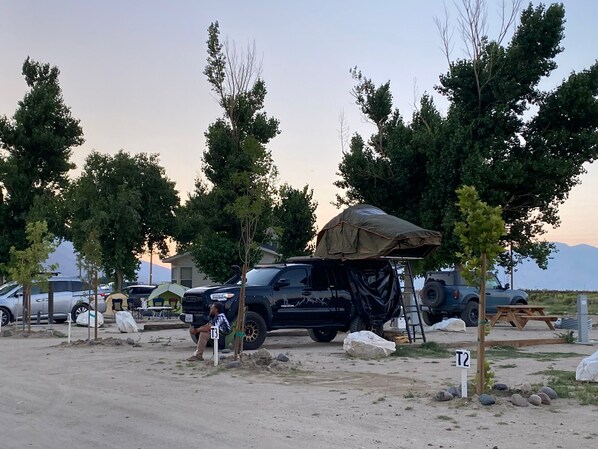 Un camping con tiendas de campaña, un SUV negro y una mesa de picnic.