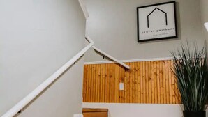 A staircase with a wooden finish, a white wall, and a framed sign with text. - GrueneGusthaus#3| Private Condo+ Golf Cart Rentals (New Braunfels)