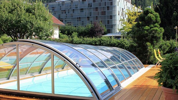A modern greenhouse structure with a curved glass roof, wooden deck, and a potted plant. - Comfortable Apartment Near Nassfeld (Hermagor-Pressegger See)