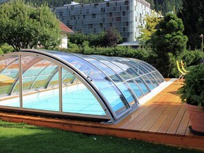 A modern greenhouse structure with a curved glass roof, wooden deck, and a potted plant. - Comfortable Apartment Near Nassfeld (Hermagor-Pressegger See)