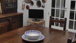 Un coin repas avec une table en bois, deux assiettes, un téléviseur et un mur décoré de bols en bois.