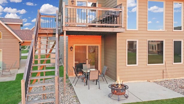 Une maison à deux étages dotée d’un balcon, d’un foyer extérieur et d’un espace patio.