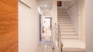 A modern interior with a wooden panel wall, a staircase, and a hallway leading to a room with a chair and a table. - The Dorm Hostel (Phuket)