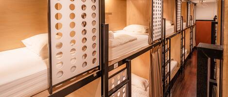 A row of bunk beds with a wooden floor and a partition with circular cutouts.