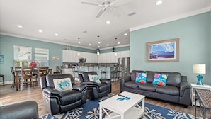 A spacious living area with leather sofas, a dining table, and a kitchen in the background. - Large Panama City Beach Home |Heated Private Pool | Easy Beach Days (Panama City Beach)