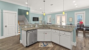A modern kitchen with granite countertops, white cabinetry, and a built-in dishwasher. - Large Panama City Beach Home |Heated Private Pool | Easy Beach Days (Panama City Beach)