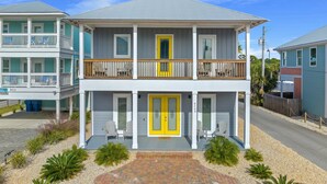 A two-story house with a balcony, a yellow door, and a number 9701 on the front. - Large Panama City Beach Home |Heated Private Pool | Easy Beach Days (Panama City Beach)