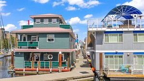 A waterfront building with a dock, a covered deck, and a small boat docked nearby. - West Bay Bliss (Victoria)