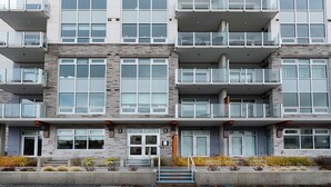 A multi-story residential building with balconies, large windows, and a stone facade. - West Bay Bliss (Victoria)