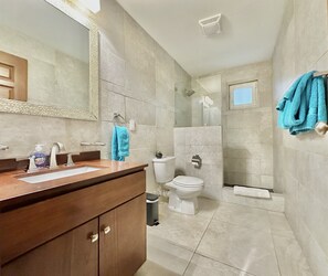 A modern bathroom with a wooden vanity, a large mirror, a toilet, and a shower area. - OASIS Apartments Simpson Bay (Simpson Bay)