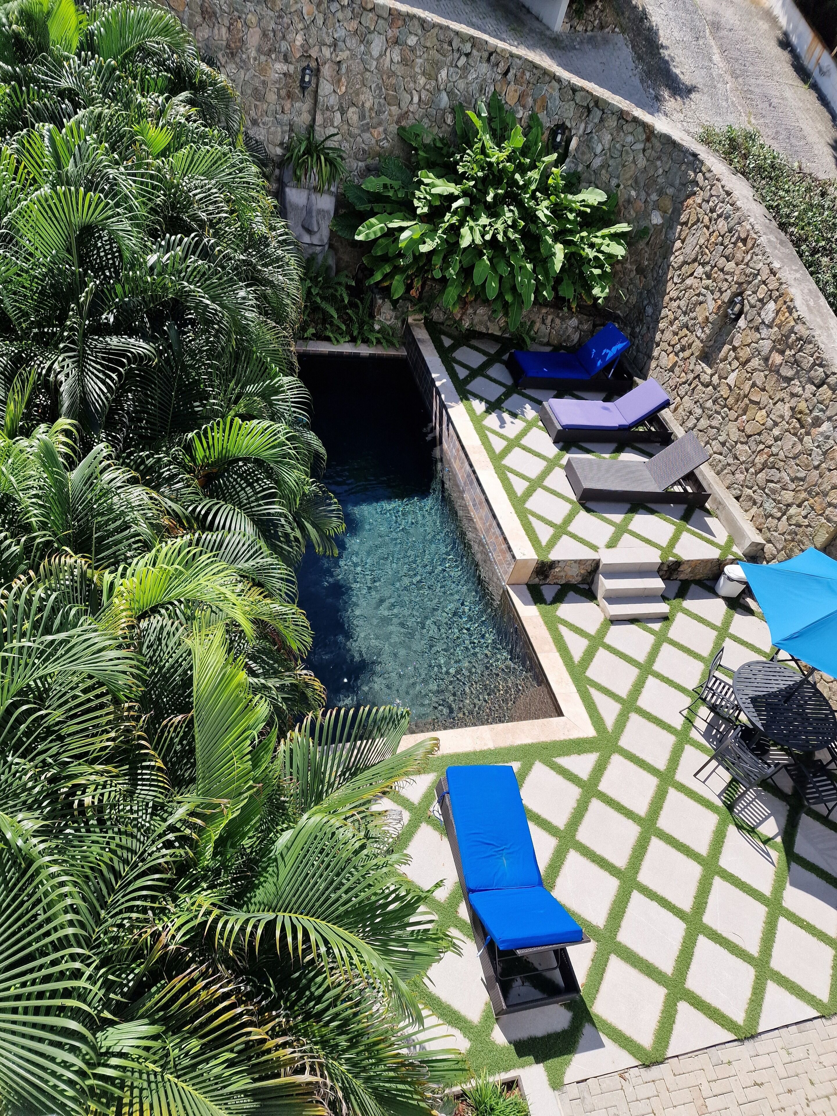 A pool area with lounge chairs and a stone wall.