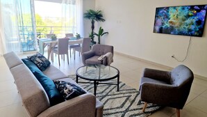 Una sala de estar moderna con un sofá, sillones, una mesa de centro y un televisor.