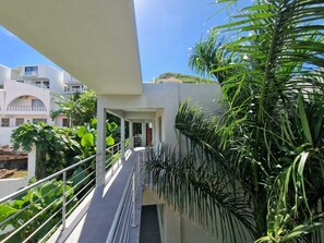 A modern building with a covered outdoor area, featuring a metal railing and lush greenery. - OASIS Apartments Simpson Bay (Simpson Bay)