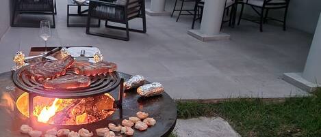 An outdoor patio with a grill, seating area, and a view of the surrounding garden.
