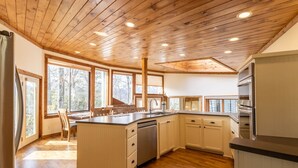 Una cocina moderna con vigas de madera en el techo, ventanas amplias y una isla central.