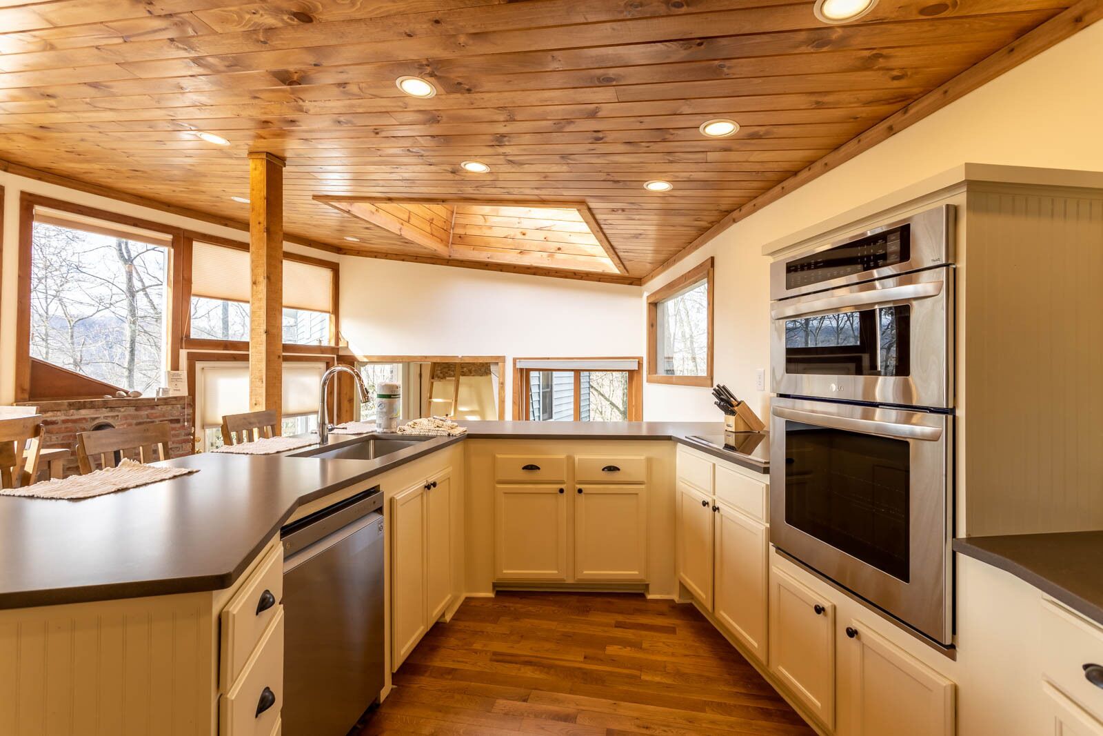 A kitchen with wooden ceiling beams, a stainless steel oven, and a sink with a faucet.