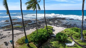 Une plage avec un rivage rocheux, des palmiers et une chaise.