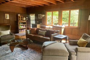 A cozy living room with a sofa, armchairs, a coffee table, and a bookshelf.