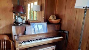 Um piano de madeira com um atrnel, um banquinho e uma lâmpada.