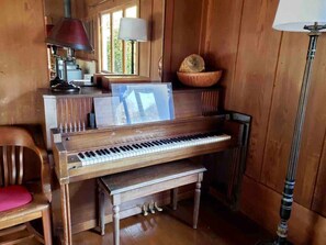 A wooden piano with a music stand, a bench, and a lamp. - Beat the Heat in our Sunny Classic Inverness Home (Inverness)