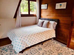 A bedroom with a bed, a window, and a wooden wall.