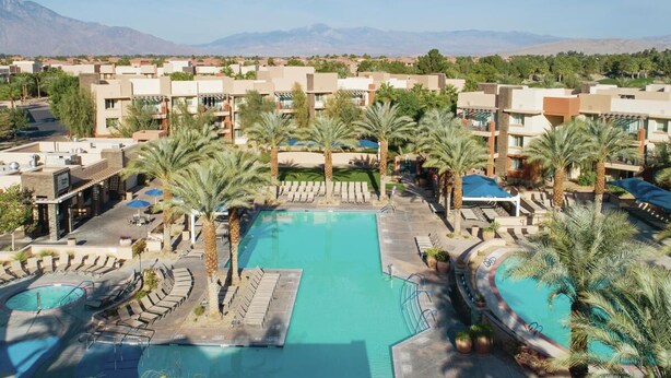 A resort with a central swimming pool surrounded by palm trees and sun loungers, with a view of distant mountains. - Coachella 2026! Marriott Shadow Ridge Enclave- First Weekend (Palm Desert)