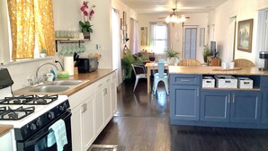 A kitchen with white cabinets, a stove, and a sink. There is a dining area with a table and chairs.