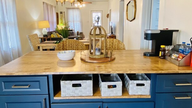 A modern kitchen with a wooden island, blue cabinets, and a chandelier.