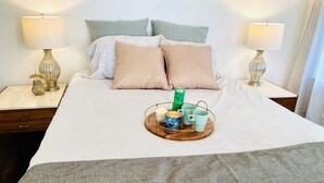 A neatly made bed with a tray of breakfast items, two bedside lamps, and a simple nightstand.
