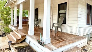 A porch with wooden steps, two chairs, and a small table.