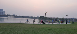 Ein Park mit einem Brunnen, Spaziergängern und einem Sonnenuntergang im Hintergrund.