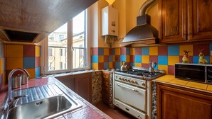 A kitchen with a large window, a gas stove, a built-in oven, and a microwave.