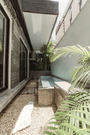 Relax by the pool surrounded by lush greenery and a modern building with large windows.