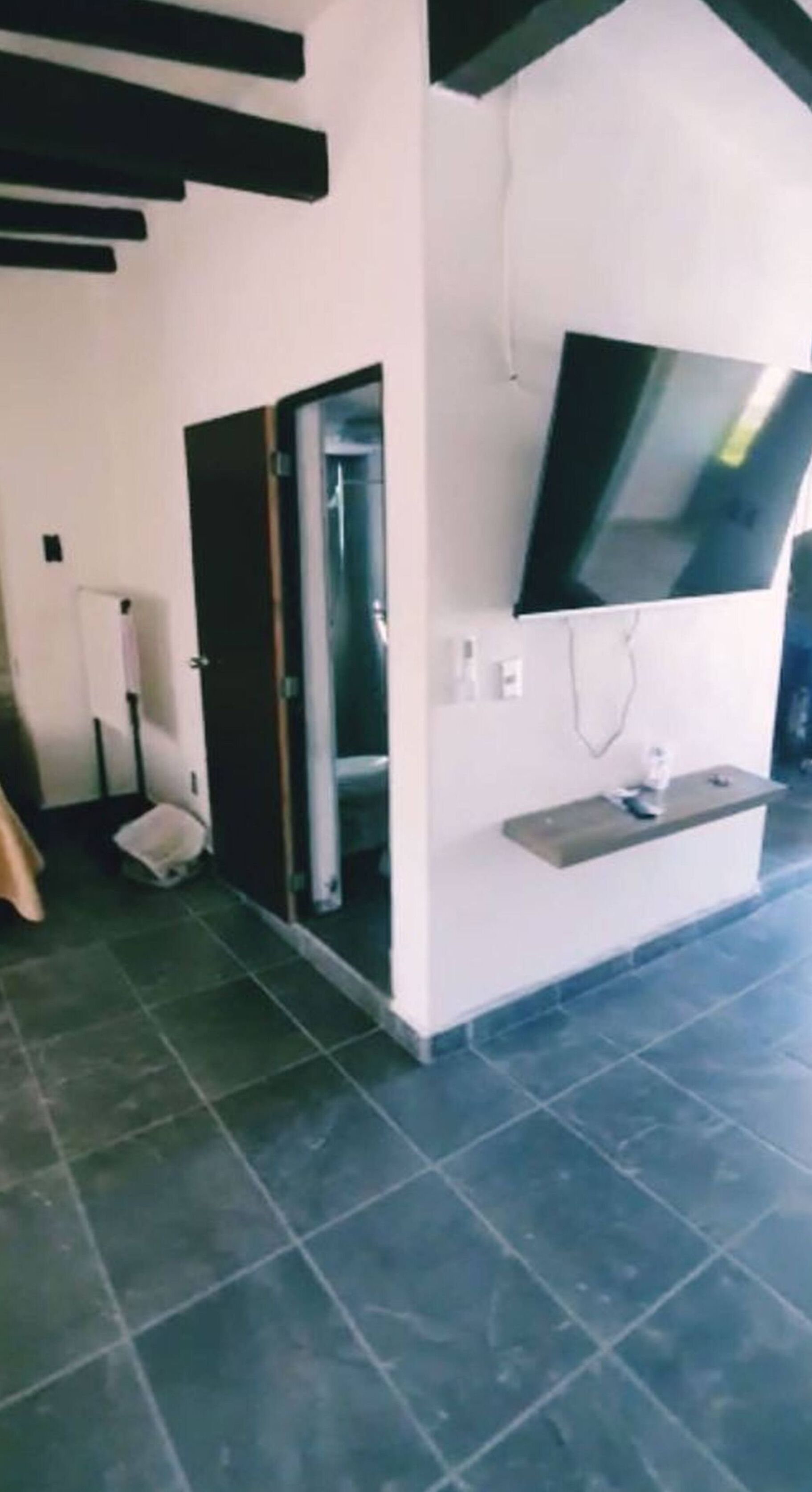 A room with a built-in TV, a door, and a small shelf.