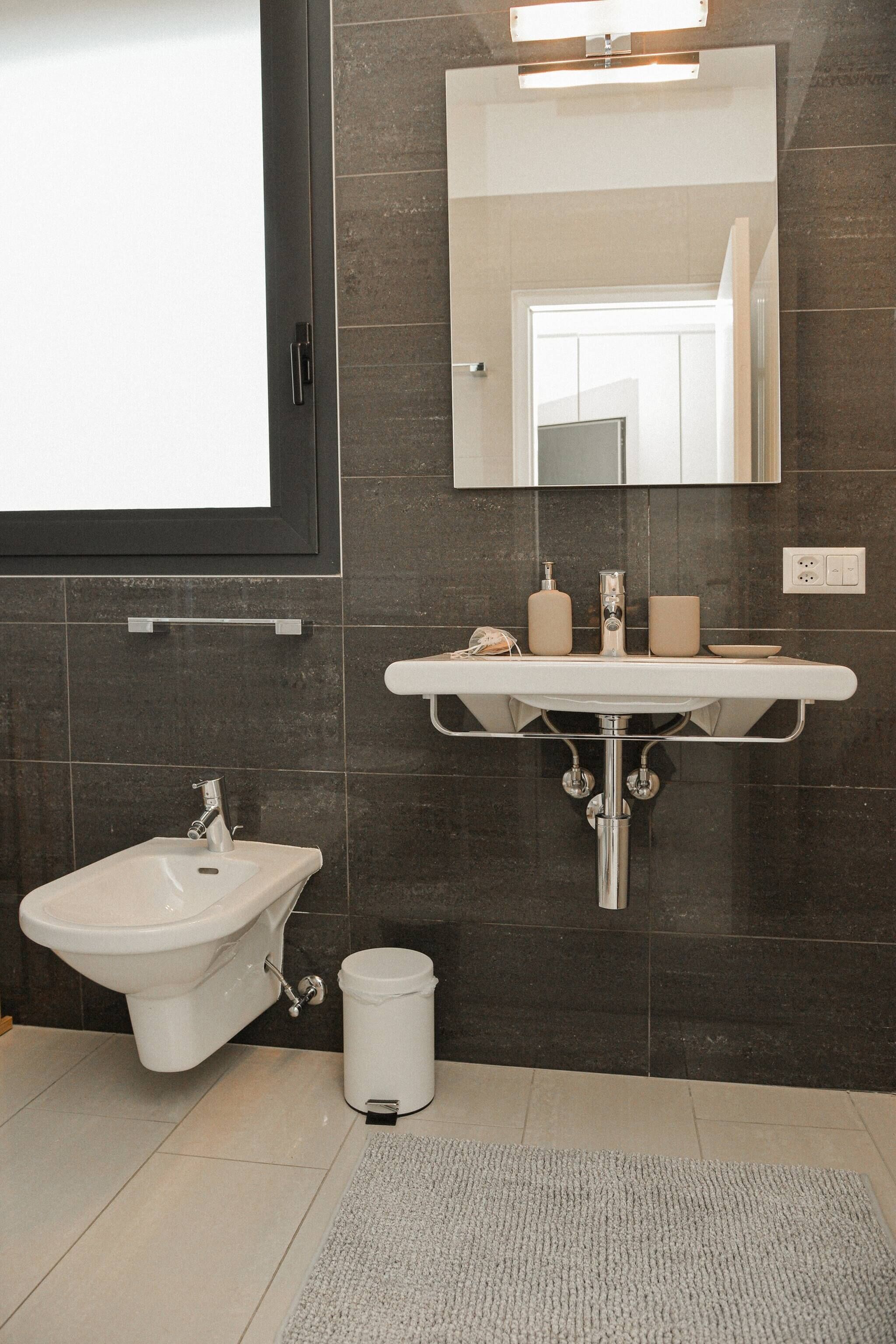 A modern bathroom with a bidet, sink, and mirror.