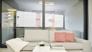 A modern living room with a beige sofa, a white coffee table, and a small potted plant.
