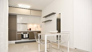 A modern kitchen with a white table and chairs, a built-in oven, and a microwave.