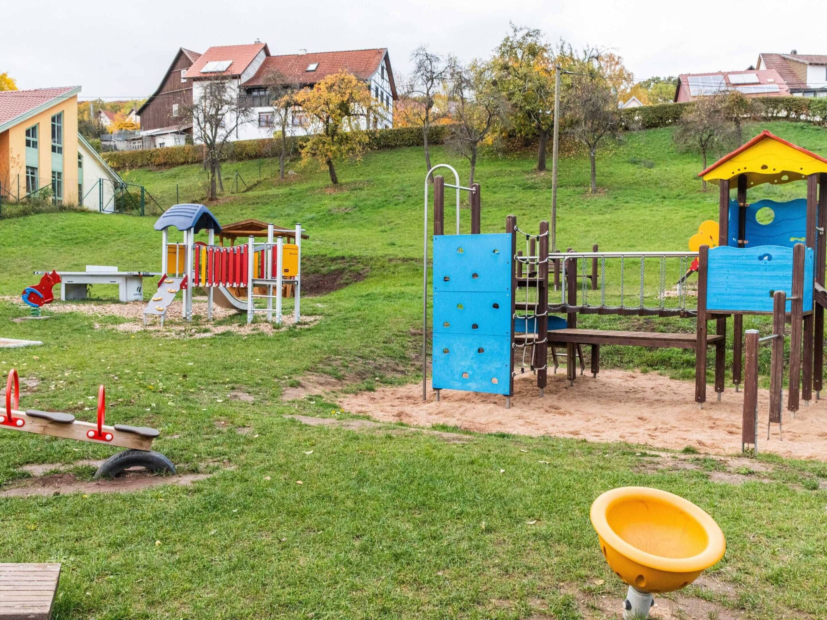 A playground with various play structures, including a slide, climbing wall, and swings.